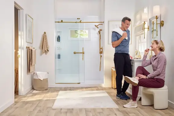 Couple beside a glass-enclosed shower with warm metal fixtures