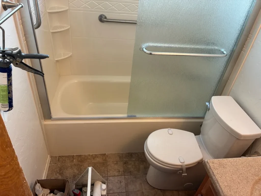New Edmond bathtub with acrylic walls, shelves, grab bars and sliding door during installation