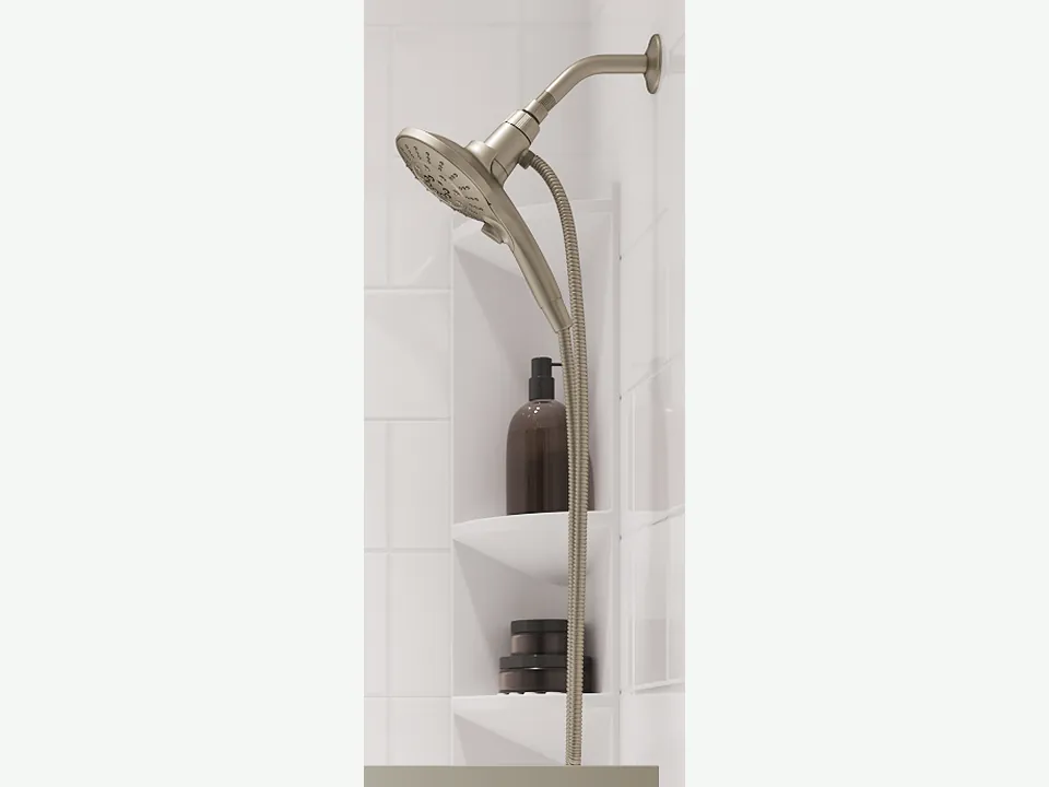 Handheld showerhead on a white acrylic shower wall, used to rinse cleaner off the walls