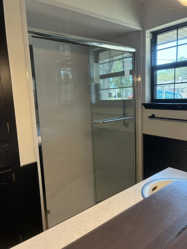 Completed Norman shower with white tile-style walls and sliding glass doors
