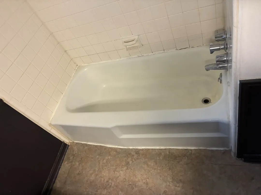 Original white bathtub and square-tile walls before a Norman shower conversion
