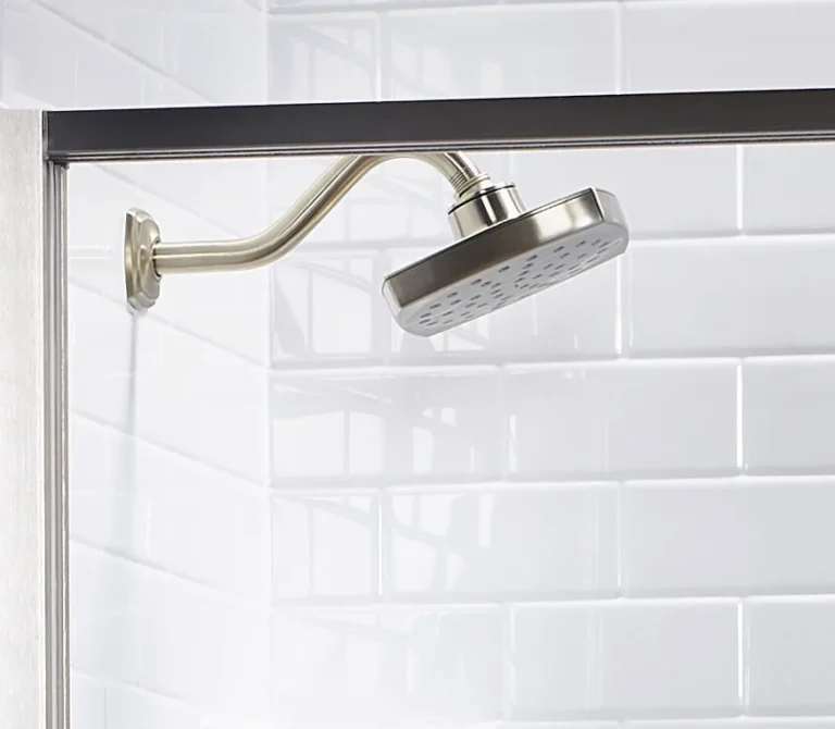 Brushed metal showerhead mounted above white subway-style Bath Fitter walls.