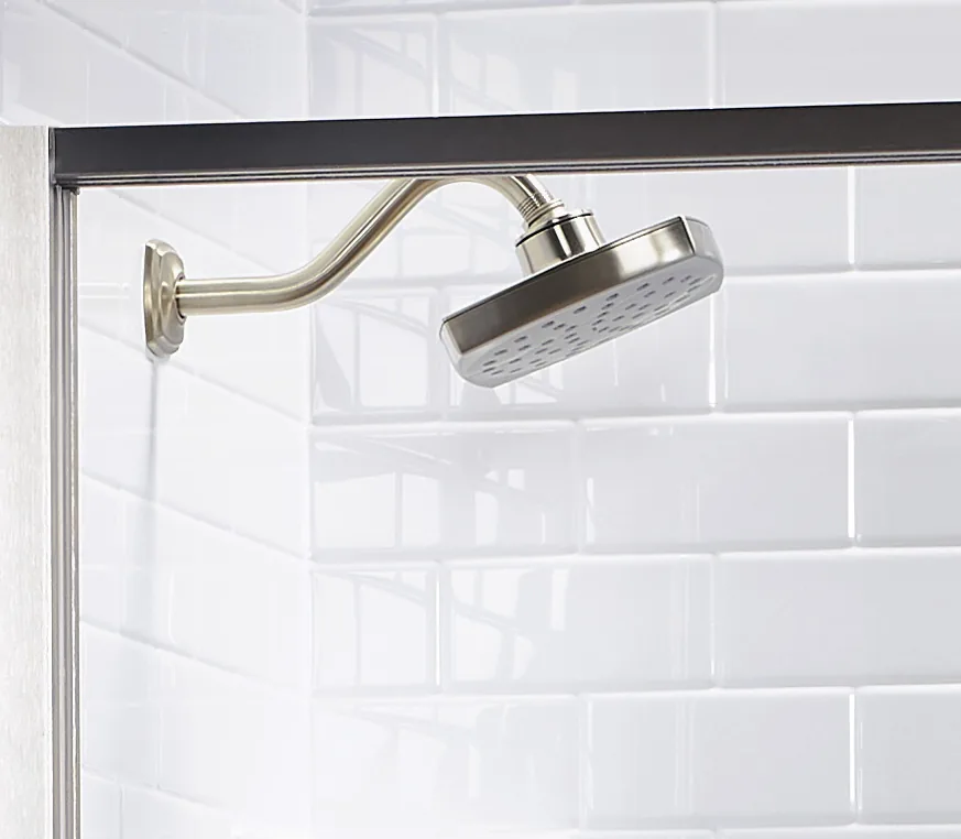 Brushed metal showerhead mounted above white subway-style Bath Fitter walls.